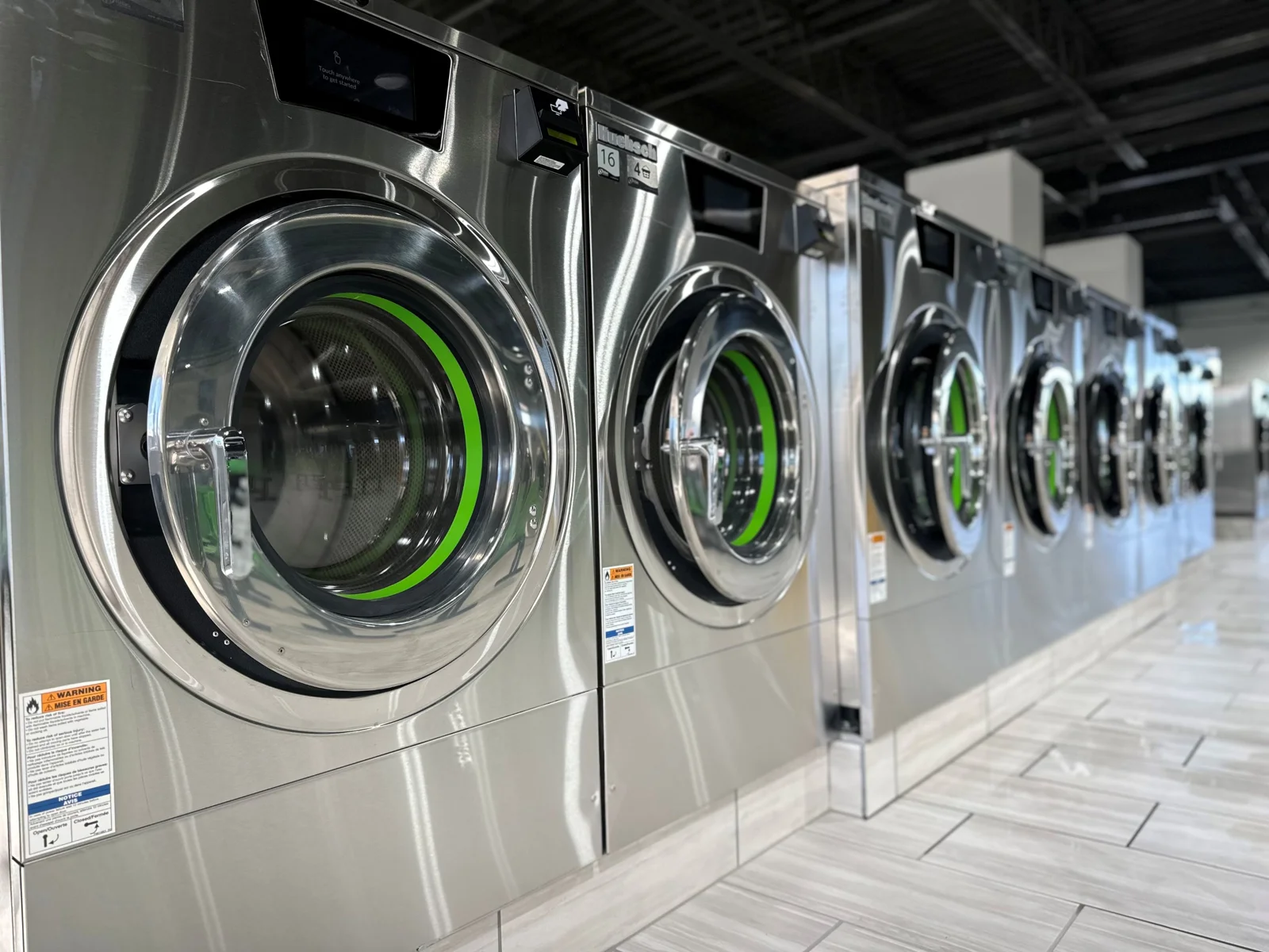 Row of stainless Huebsch front-load washers at Dustoff